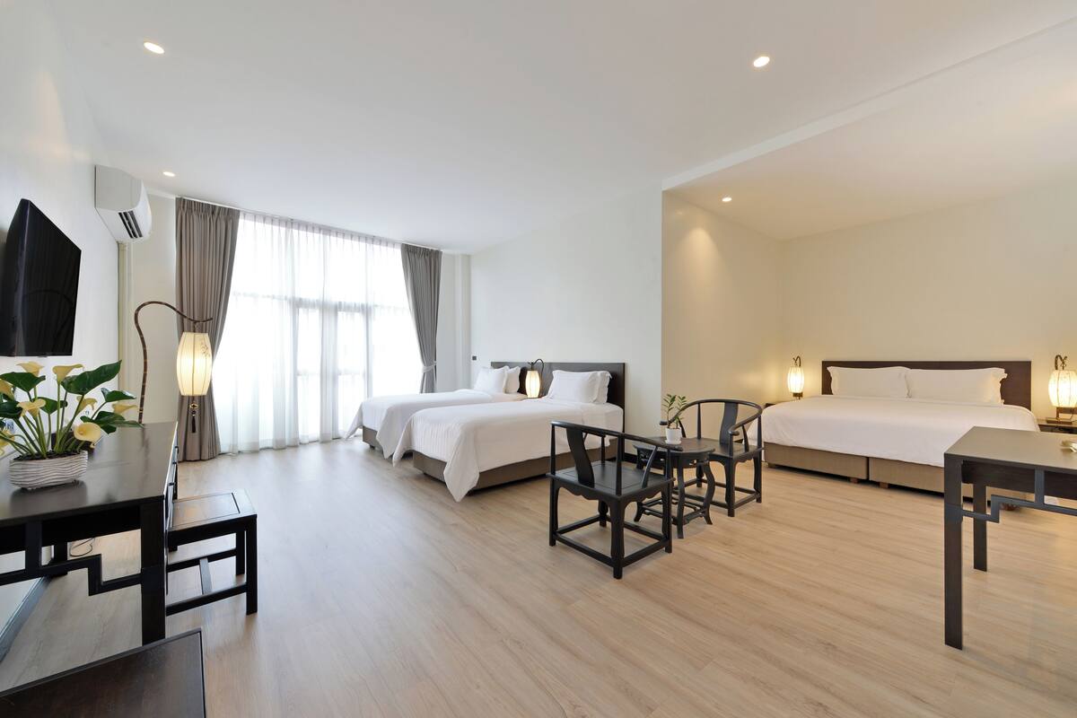 A hotel room with two beds, a dining table, and a seating area.