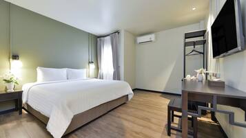 Una habitación de hotel con cama, mesita de noche, lámpara, aire acondicionado y un escritorio con silla.