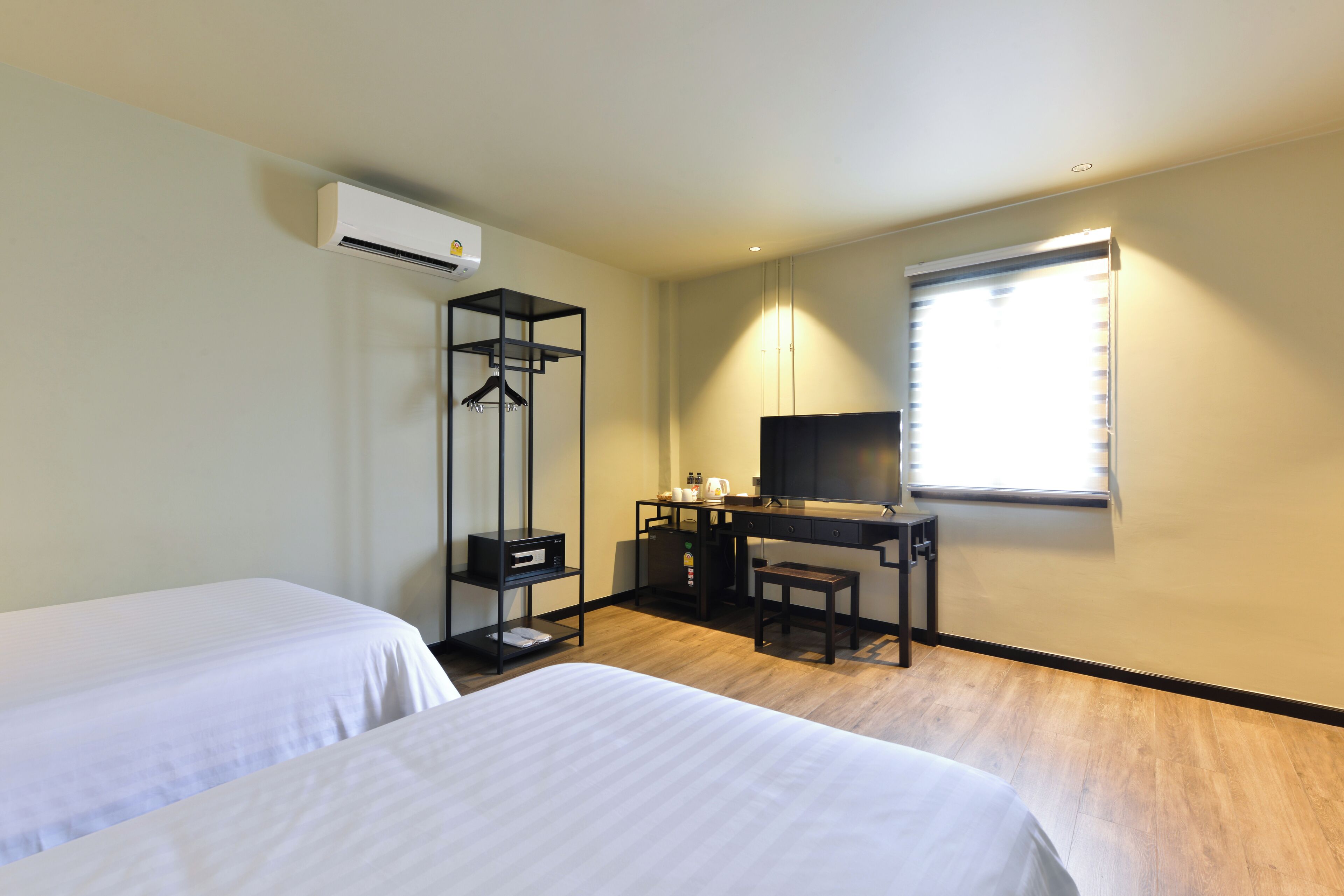 A hotel room with two beds, a desk, a television, and a wardrobe.