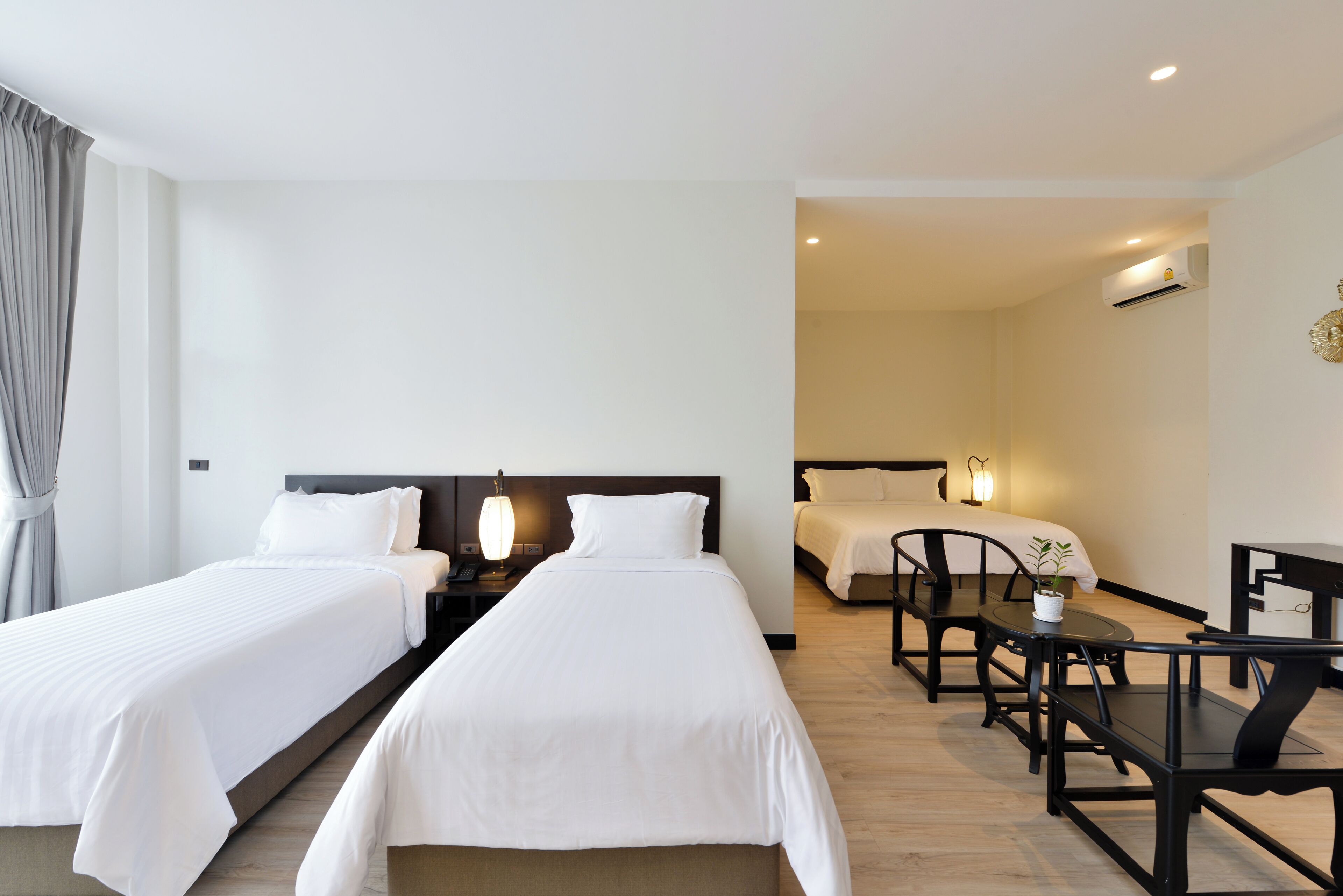 Ein Hotelzimmer mit zwei Betten, einem Esstisch und einer kleinen Sitzecke.