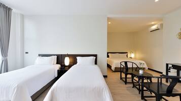 Ein Hotelzimmer mit zwei Betten, einem Esstisch und einer kleinen Sitzecke.