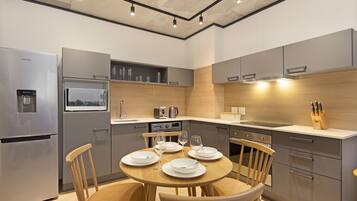 A modern kitchen with grey cabinetry, a built-in microwave, and a dining table set for four.