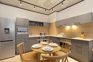 A modern kitchen with grey cabinetry, a built-in microwave, and a dining table set for four. - Bridgewater View 502 (Cape Town)