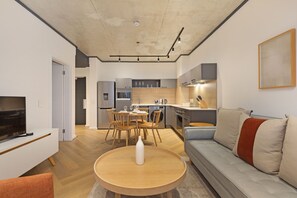 Uma sala de estar moderna com televisão, sofá e área de jantar.