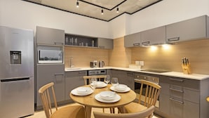A modern kitchen with grey cabinetry, a built-in microwave, and a dining table set for four. - Bridgewater View 502 (Cape Town)