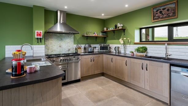 Une cuisine moderne dotée d’un îlot central, d’appareils électroménagers en acier inoxydable et de murs peints en vert.