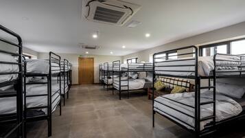 Un dormitorio con literas, una puerta de madera y un respiradero en el techo.