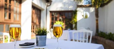 Una mesa con dos copas de vino, un cuenco de aceitunas y una pequeña planta en maceta.