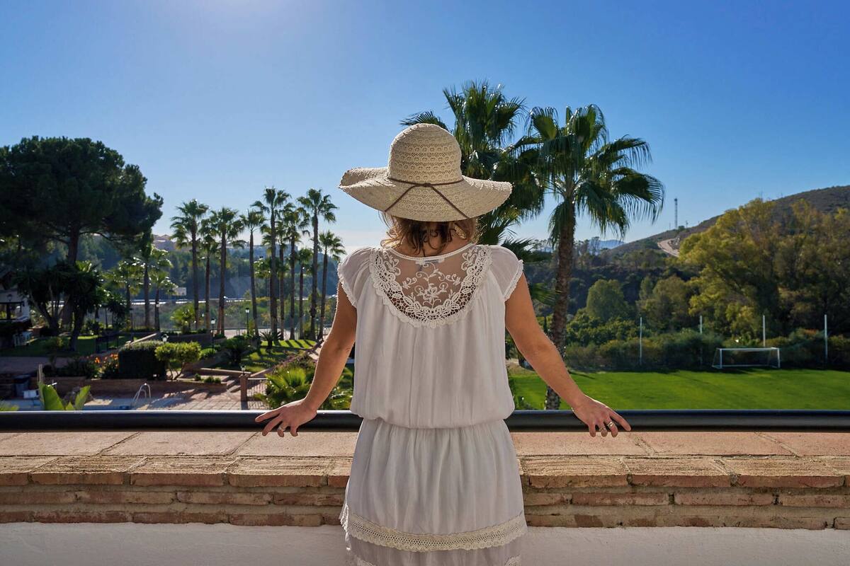 Una persona de pie junto a una barandilla, con vista a un parque y un campo de fútbol.