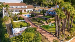 A large, white villa with a swimming pool, surrounded by palm trees and well-maintained gardens. - Hotel Alhaurín Golf Resort (Alhaurin el Grande)