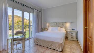 Une chambre avec un grand lit, une chaise, une table de chevet et une vue sur l’extérieur.