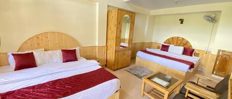 A hotel room with two wooden beds, a small table, a chair, and a mirror.