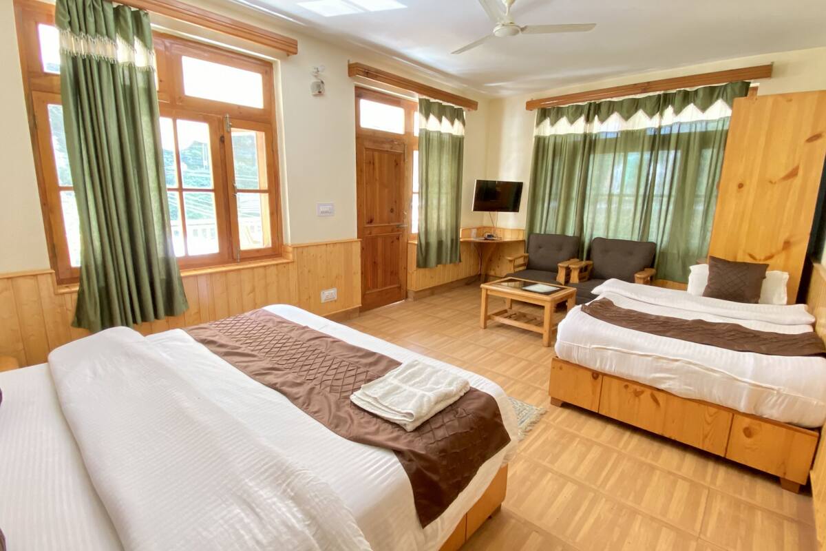 A hotel room with two beds, a TV, a desk, and a chair.