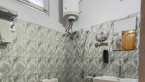 A bathroom with a toilet, sink, and a water heater mounted on the wall. - Hotel Purnima River View (Bhuntar)