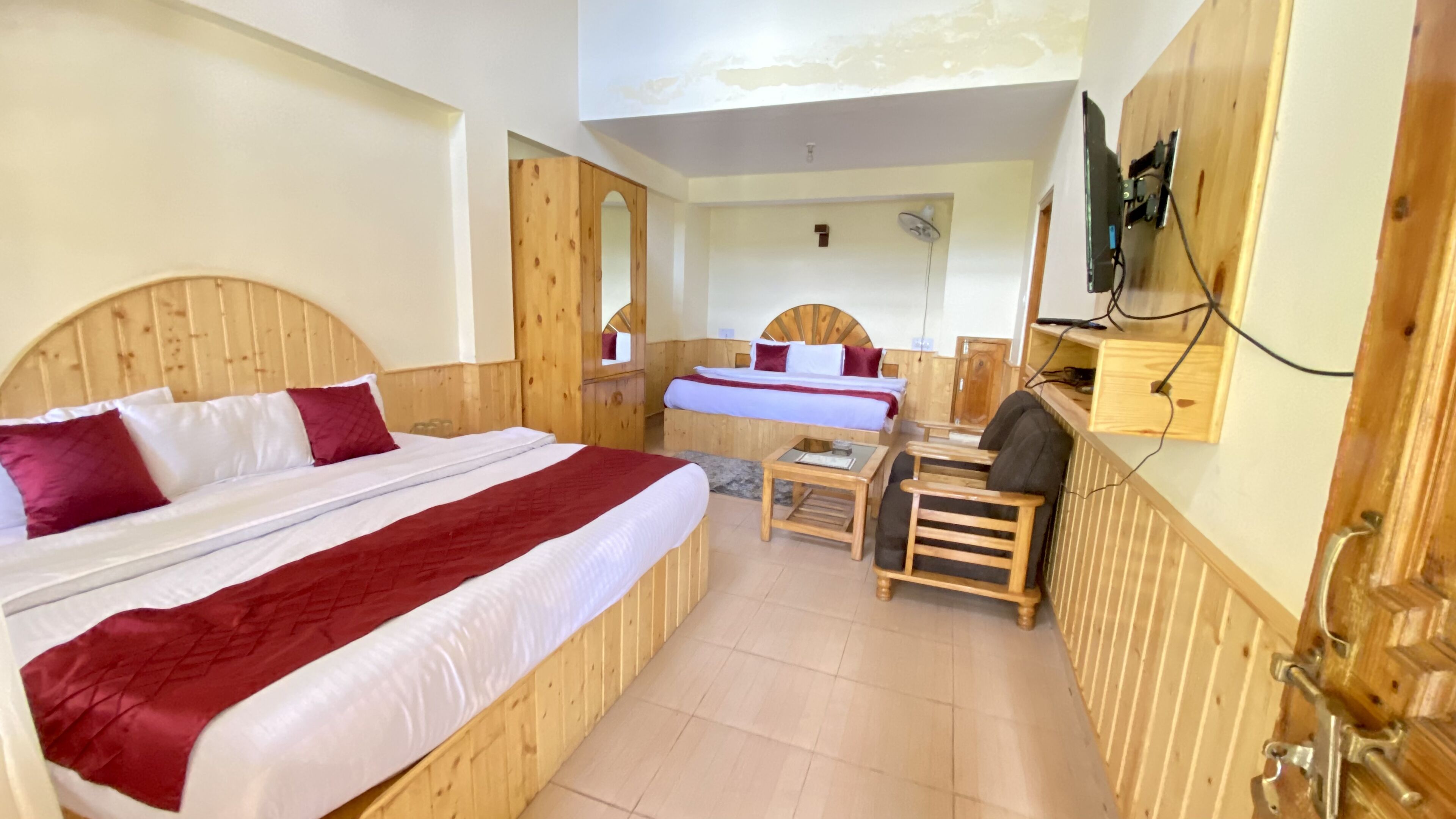 A wooden room with two beds, a small table, and a chair.