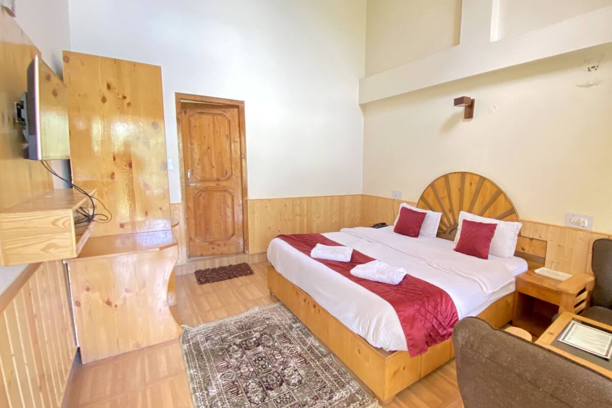 A wooden room with a bed, a desk, and a chair.