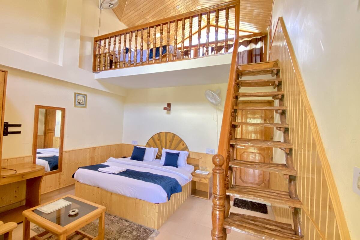 A room with a wooden bed, a desk, a mirror, and a staircase.