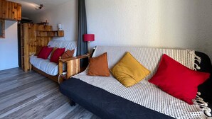 A cozy room with a bed, a sofa, a lamp, and a wooden shelf. - Cozy Mini T2 in Barcelonnette - For 4, sunny balcony (Barcelonnette)