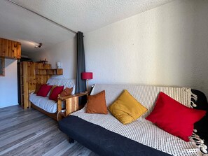 A cozy room with a bed, a sofa, and a small wooden table.