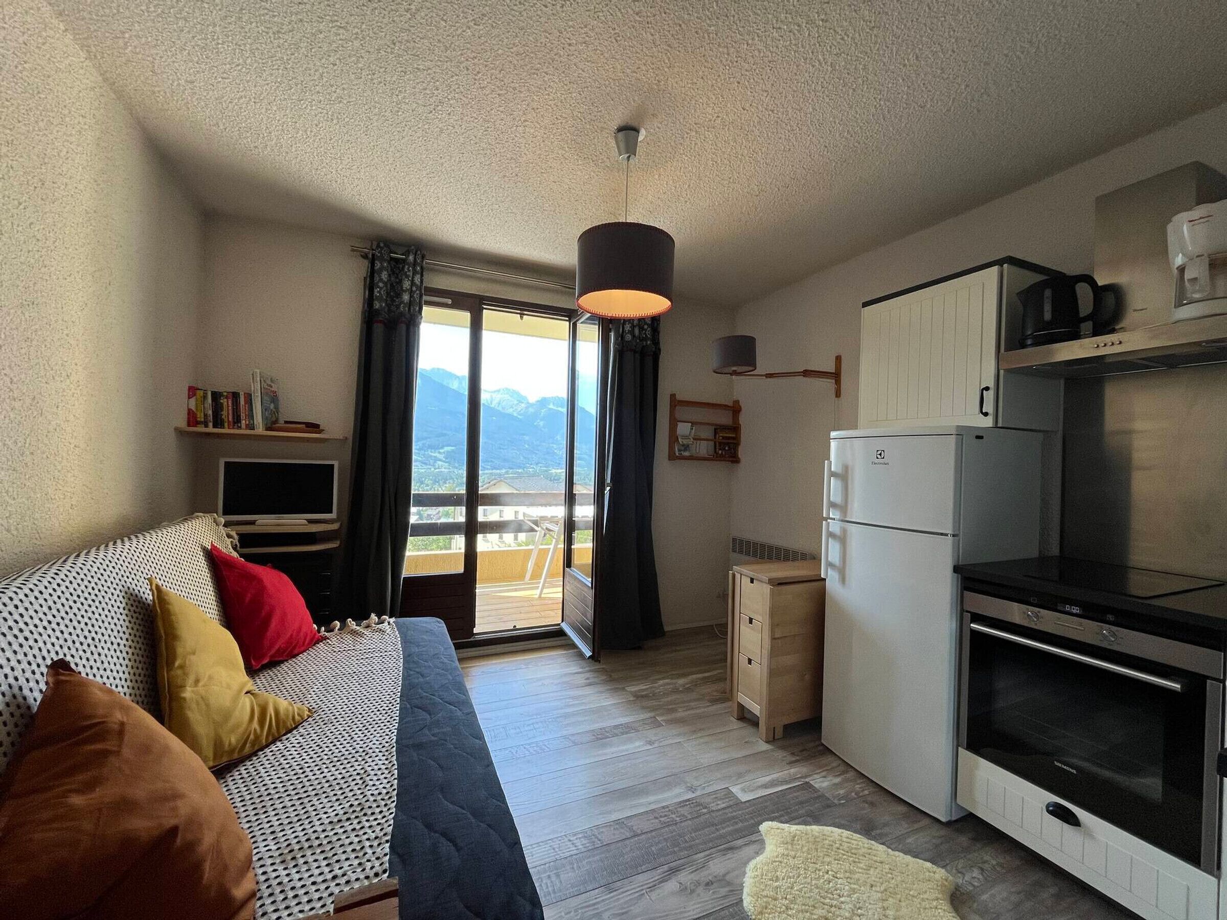 Une chambre avec un lit, une télévision et un balcon offrant une vue sur la montagne.