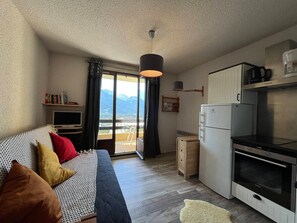 A bedroom with a bed, a TV, and a balcony with a mountain view.