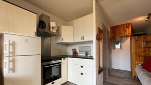 A compact kitchen with white cabinets, a built-in oven, and a coffee maker. - Cozy Mini T2 in Barcelonnette - For 4, sunny balcony (Barcelonnette)