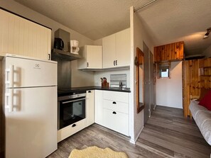 A compact kitchen with white cabinetry, a built-in oven, and a coffee maker.