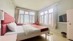 A bedroom with a bed, a chair, a TV, and a window with a view of the outdoors. - Hotel Meadows (Manali)