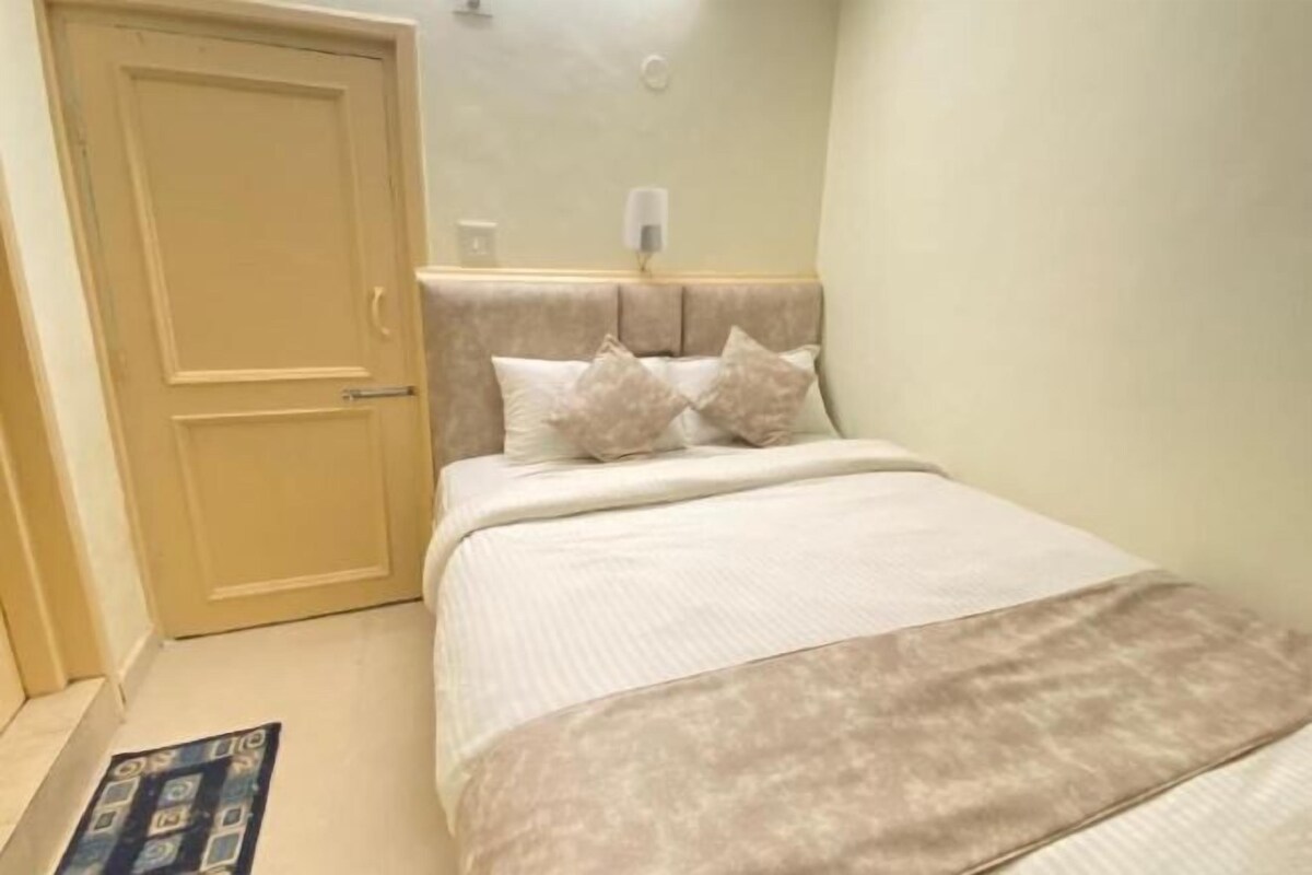 Quarto com cama, porta e luminária fixada na parede.