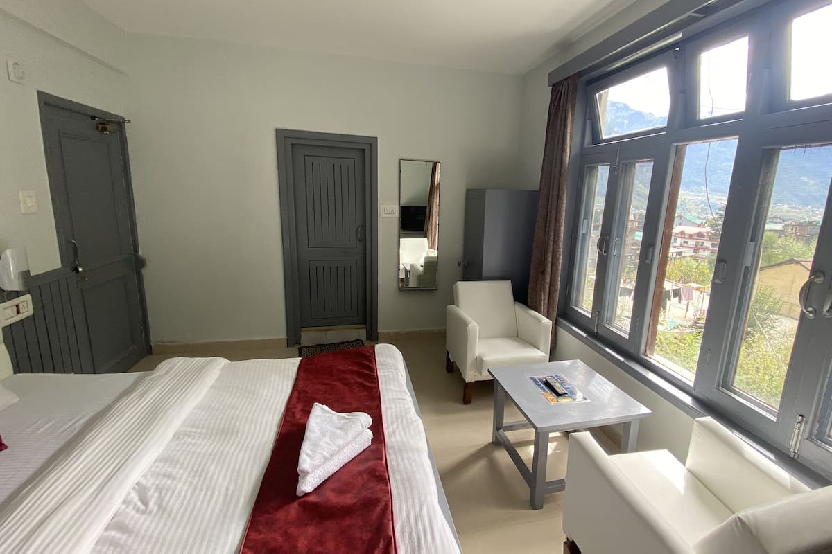 Hotellihuone, jossa on sänky, työpöytä, tuoli ja suuri ikkuna, josta on näkymä ulos.