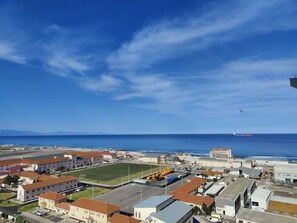 A coastal town with buildings, a clear sky, and a ship in the distance. - Best views in Gibraltar, everything within walking distance. (Gibraltar)