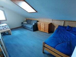 Ein Zimmer mit einem Bett, einer Couch, einem Holzschrank und einem kleinen Tisch.