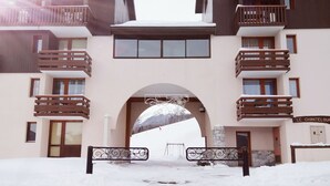 Entrada cubierta de nieve a un edificio con balcón y un letrero que dice "LE CHANTELOUF".