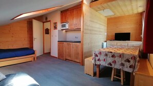 Habitación pequeña con cama, kitchenette y un pequeño comedor.
