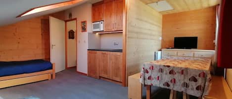 A compact room with a bed, kitchenette, and a small dining area.