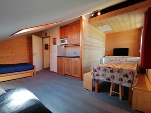A compact room with a bed, kitchenette, and a small dining area.