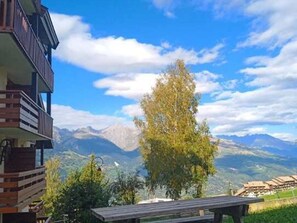 Vista de la montaña con un banco de madera y un edificio con balcones.