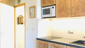 Una cocina con armarios de madera, microondas integrado y encimera negra.