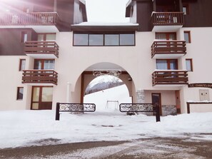 A snow-covered entrance to a building with a balcony and a sign that reads "LE CHANTELOUF".