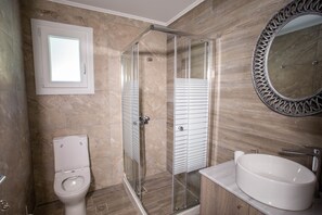 A modern bathroom with a glass-enclosed shower, a toilet, and a freestanding sink.