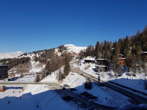 A snow-covered mountain town with buildings, a ski lift, and a road.