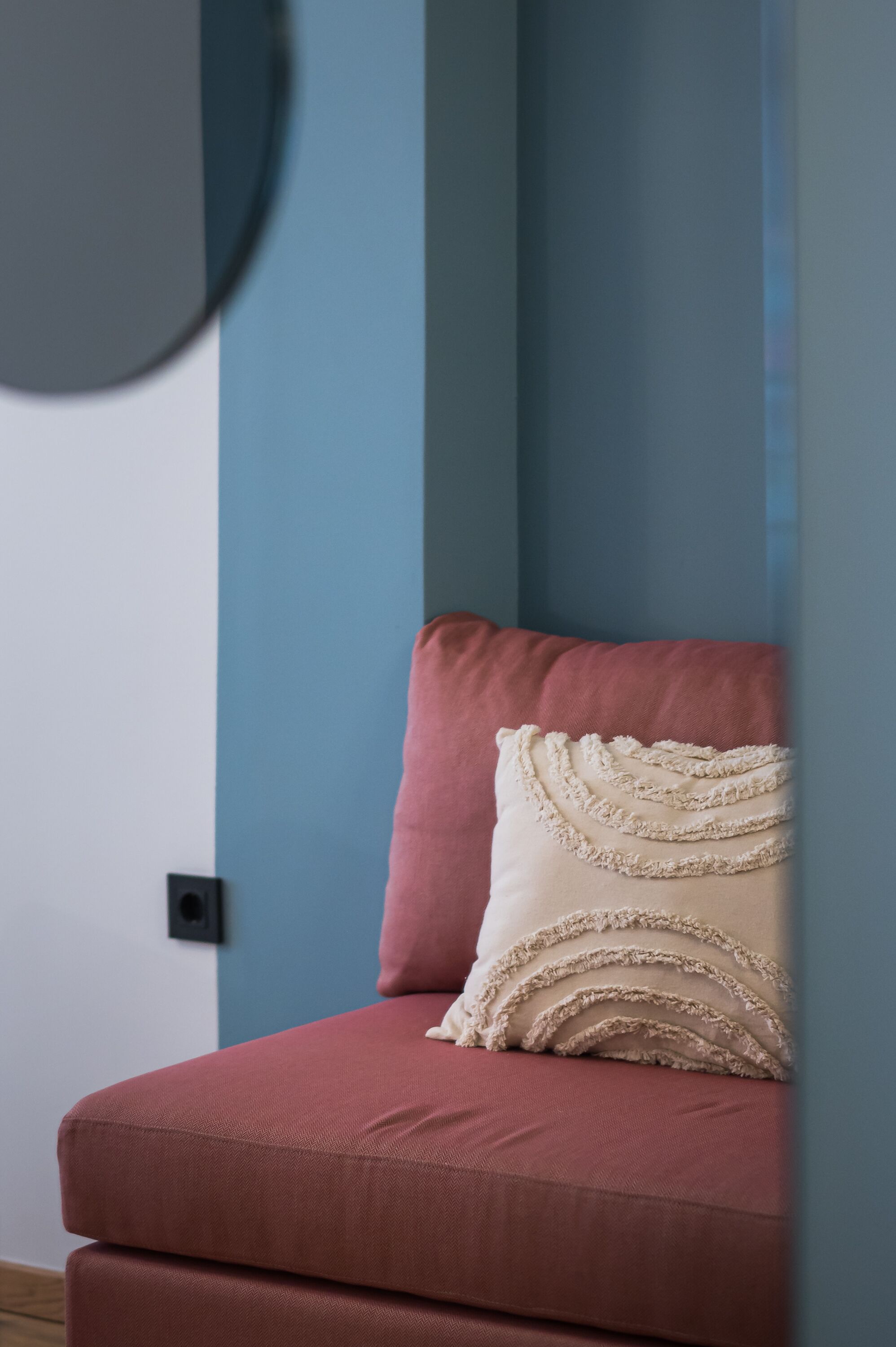 A room with a red sofa and a cream-colored pillow with a textured design.
