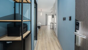 Un couloir doté d’un plancher en bois, d’un meuble de rangement noir et d’une porte moderne équipée d’un clavier pour l’ouverture à code.