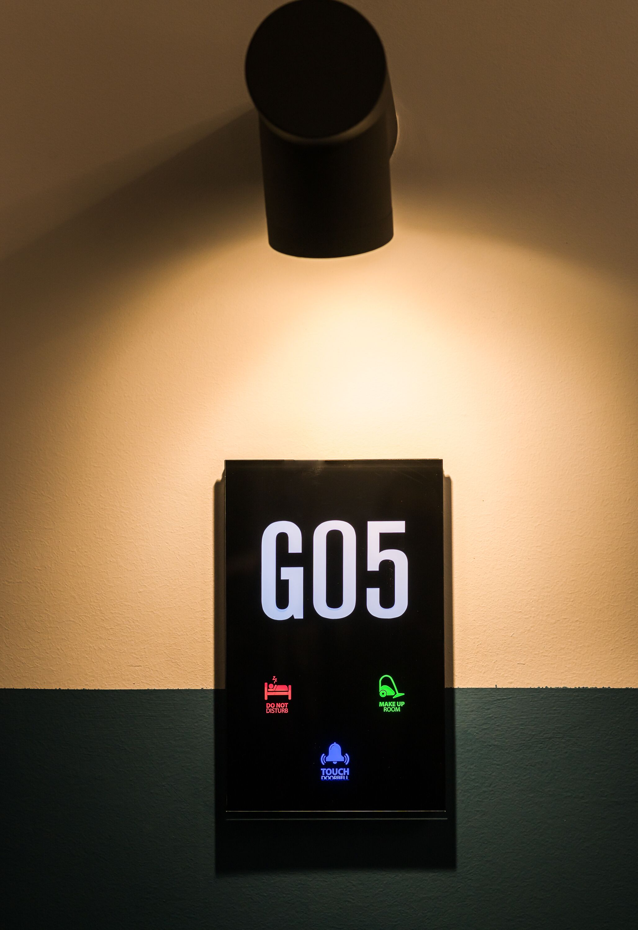 Segnaletica a parete con il numero "G05" e icone che indicano "Non disturbare", "Pulire la stanza" e "Tastiera touch".