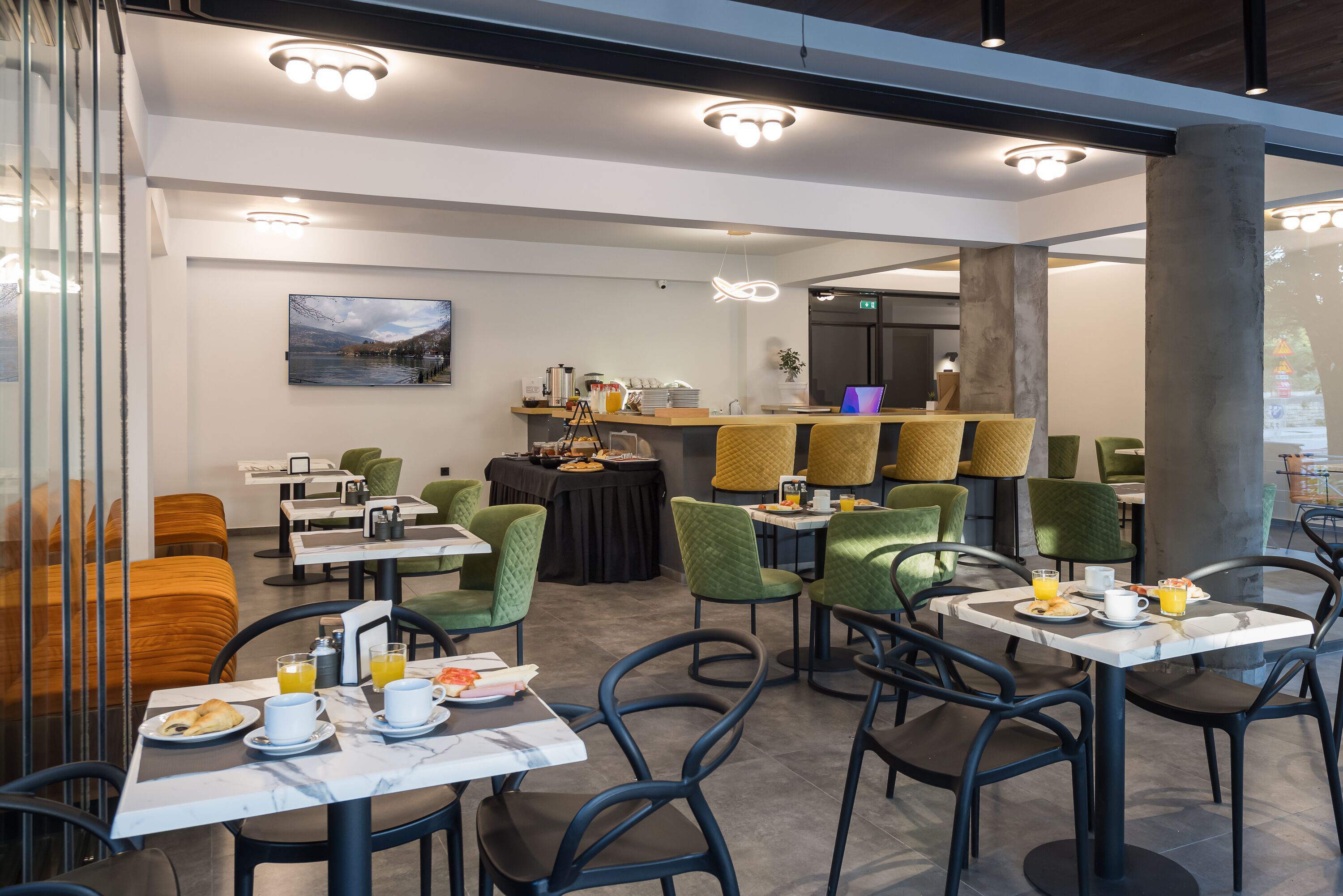 A modern dining area with tables and chairs, a bar, and a painting on the wall.