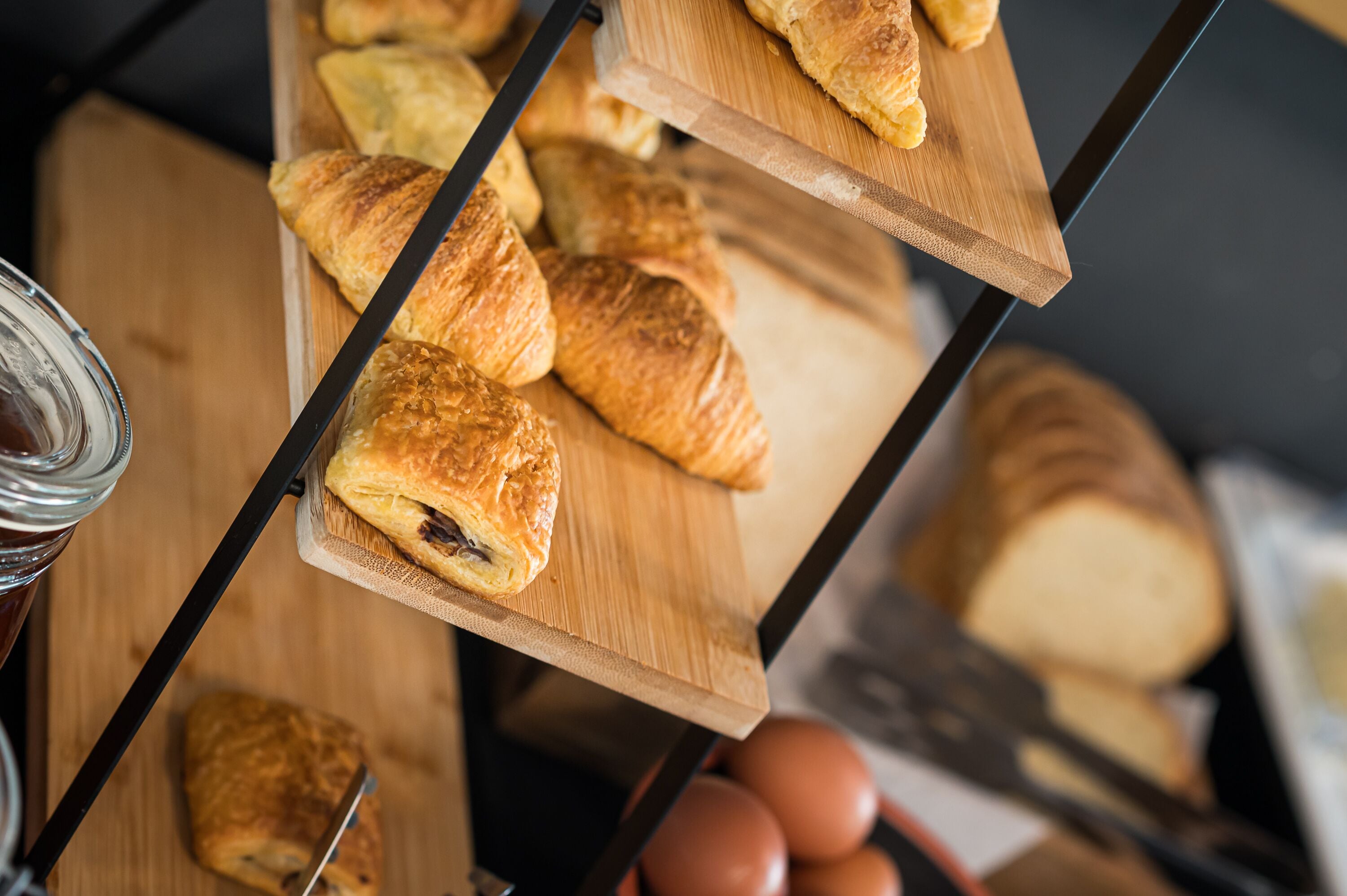 Una estructura de madera sostiene varios croissants y una hogaza de pan.