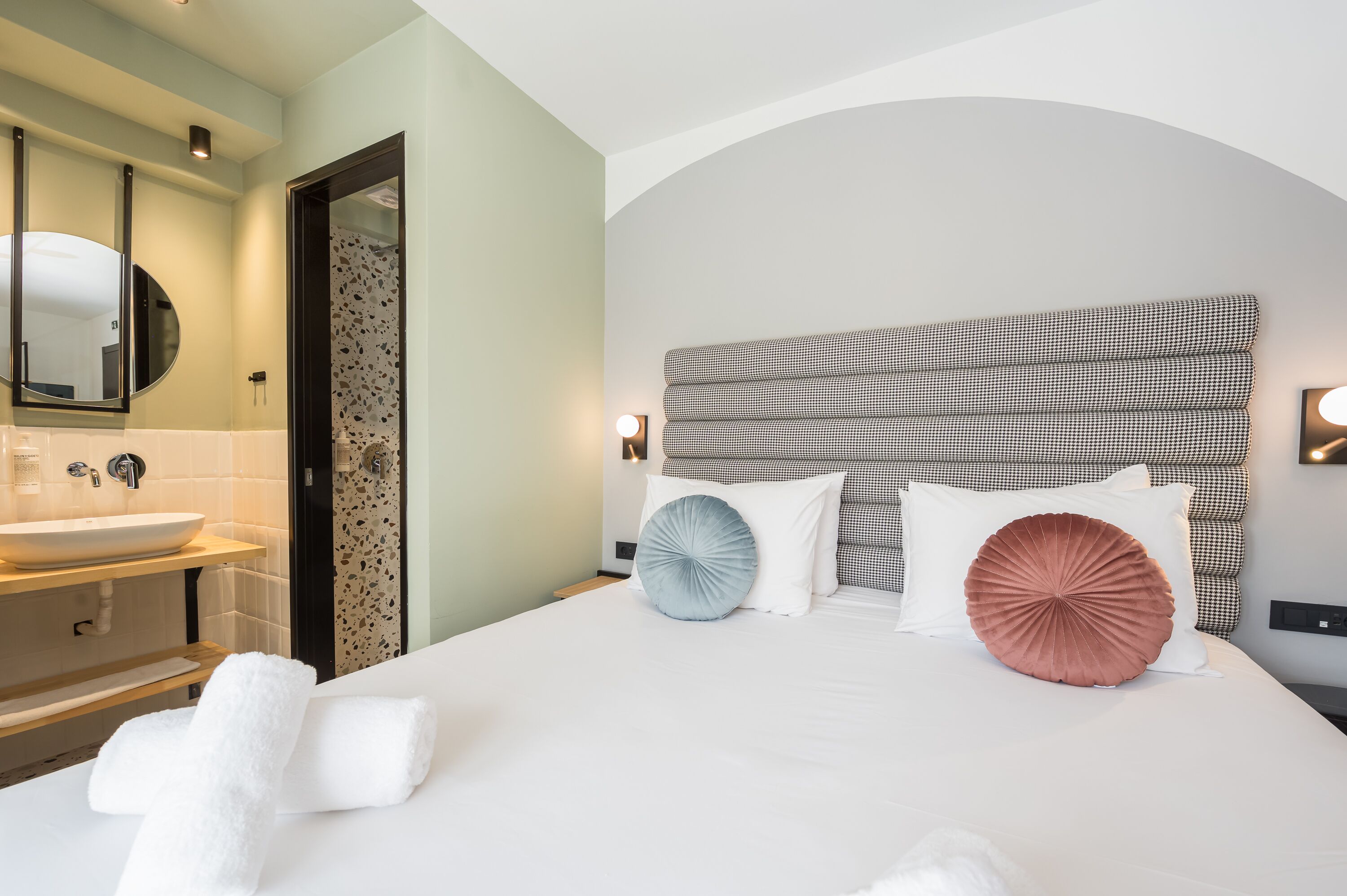 Ein Hotelzimmer mit einem großen Bett, einem Badezimmer mit Waschbecken und einem Spiegel.