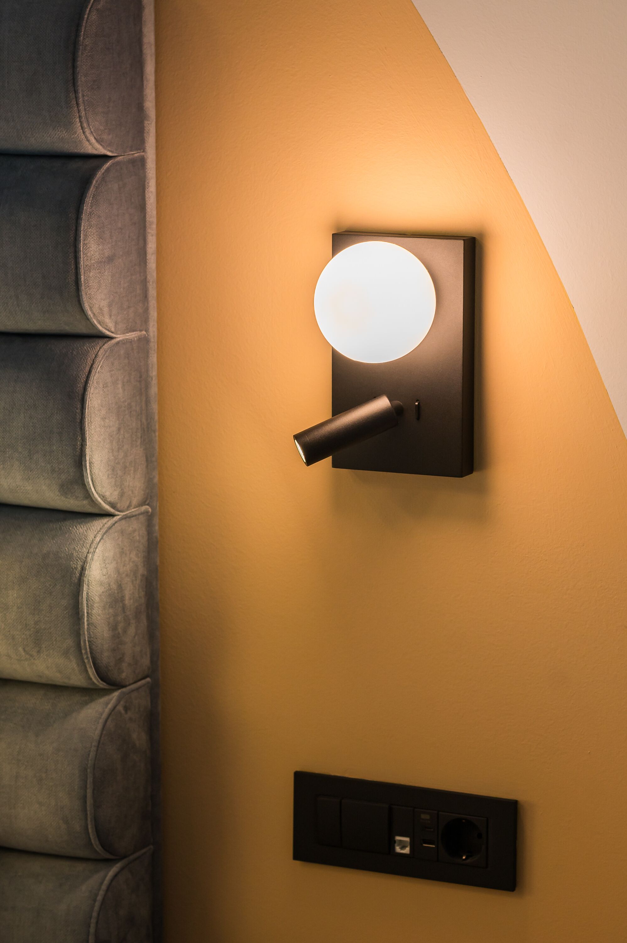Eine moderne Wandleuchte mit kreisförmigem Lampenschirm und Schalter, an einer strukturierten Wand befestigt.