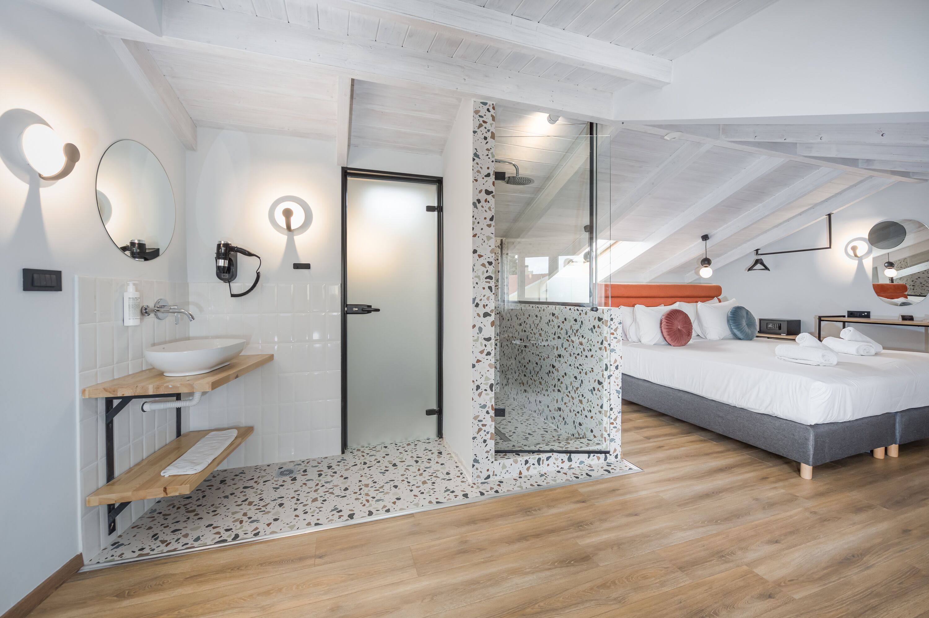 A modern bedroom with a large bed, a bedside table, a nightstand, and a built-in bench.