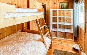 Une chambre avec un lit superposé, une échelle, une étagère blanche et une fenêtre donnant sur un beau paysage.